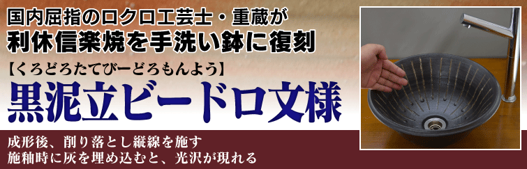 国内屈指のロクロ工芸士重蔵が利休信楽焼を手洗い鉢に復刻。黒泥立ビードロ文様(くろどろたてびーどろもんよう)は成形後、削り落とし縦線を施す。施釉時に灰を埋め込むと、光沢が現れる。